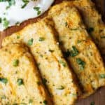 four cauliflower hash browns on a cutting board with an egg