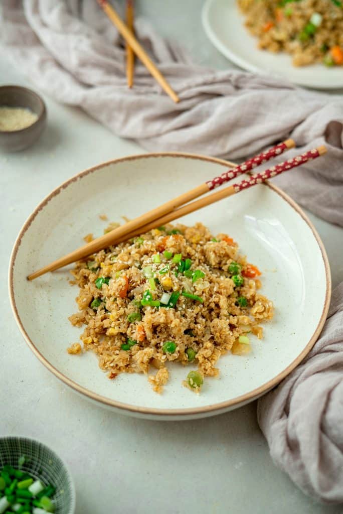 Cauliflower Fried Rice serving of cauliflower fried rice with chopsticks in a bowl