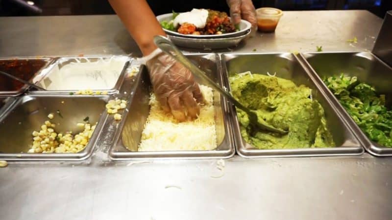a dish being made by a chipotle employee