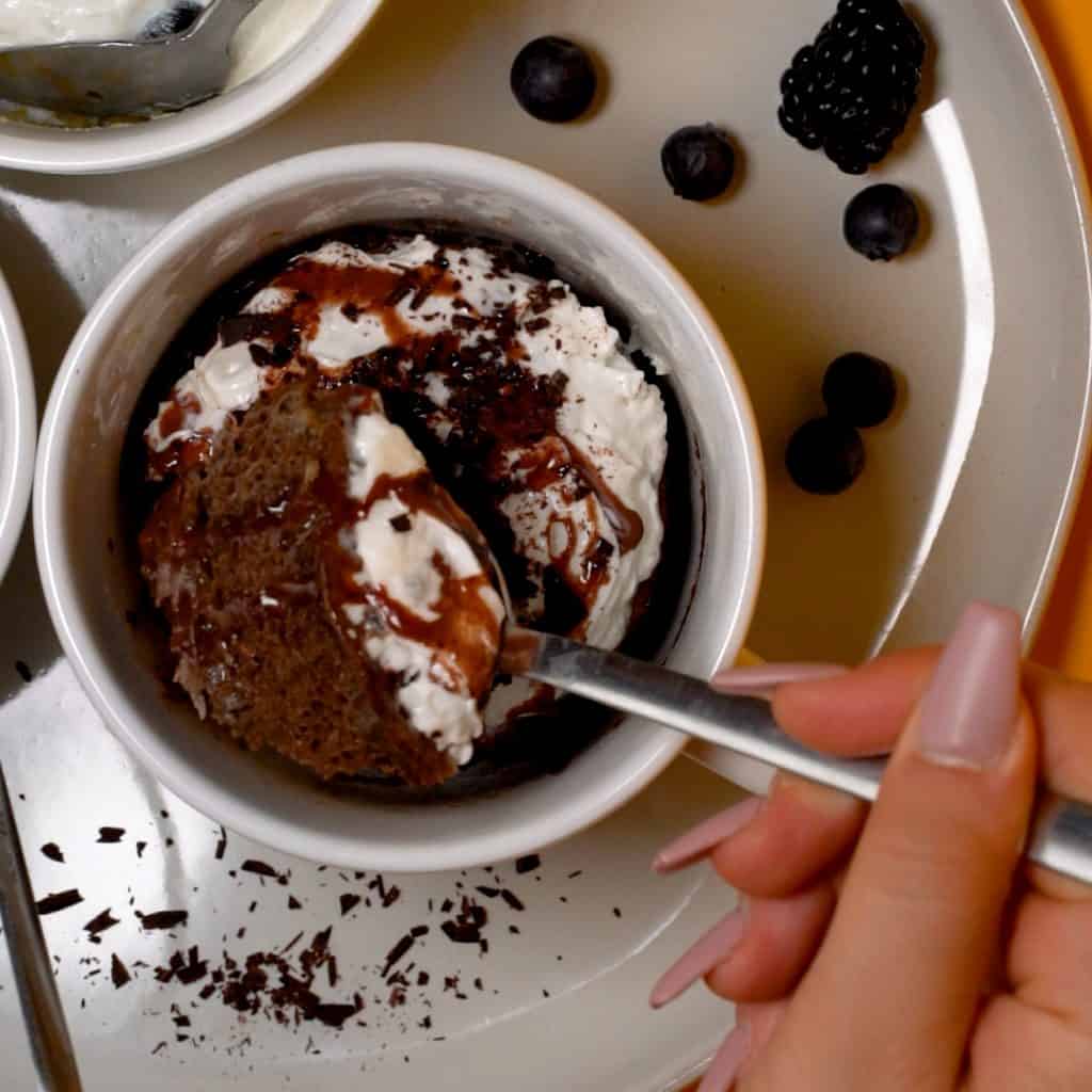keto Mug Cake chocolate cake with whipped cream and a spoon taking a piece