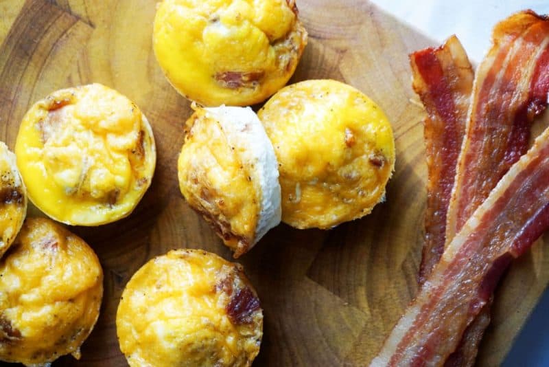 bacon egg cups and cooked bacon on a wooden cutting board a great recipe for keto on a budget