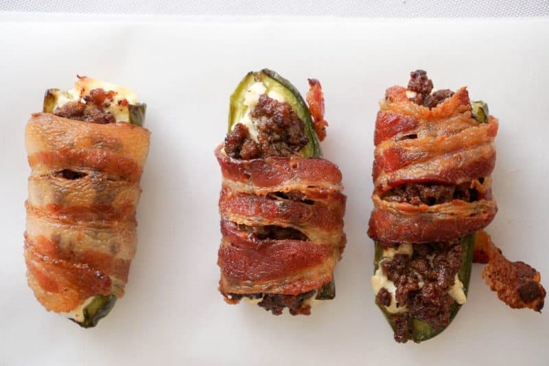 three jalapenos filled with sausage and cream cheese wrapped in bacon