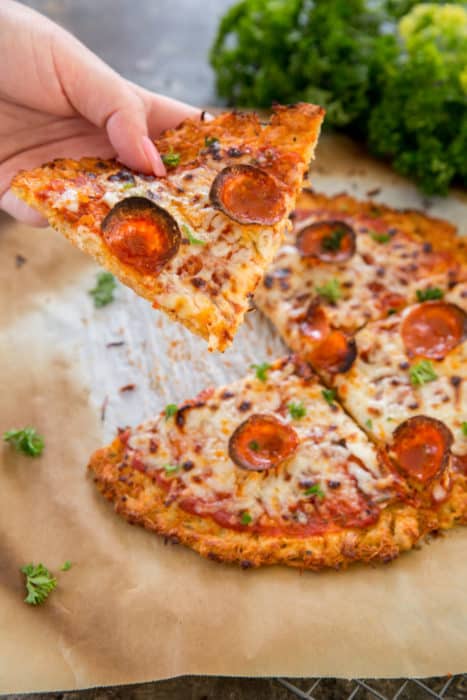 chicken crust pizza pizza sliced into four pieces and being grabbed