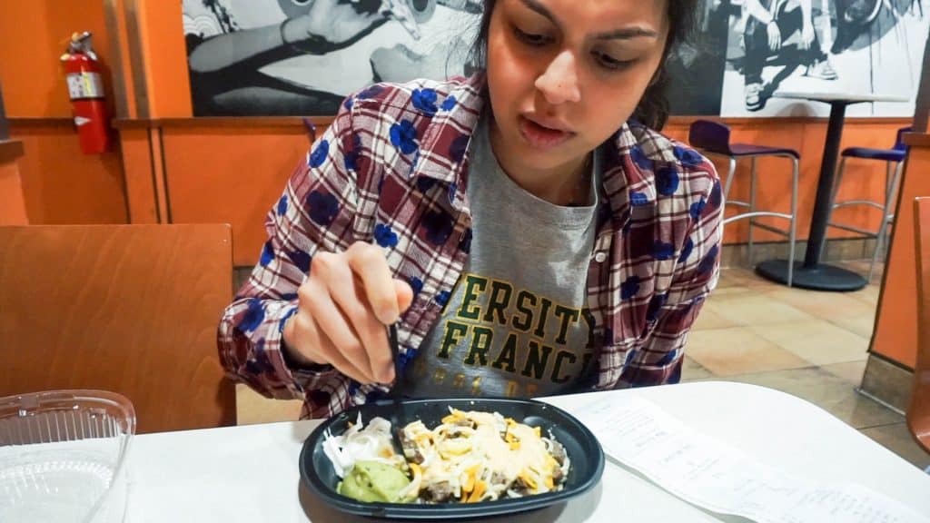 eating a taco bell breakfast bowl in a booth at taco bell