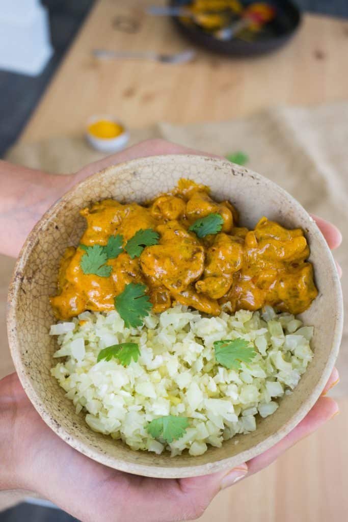 one bowl of butter chicken being held