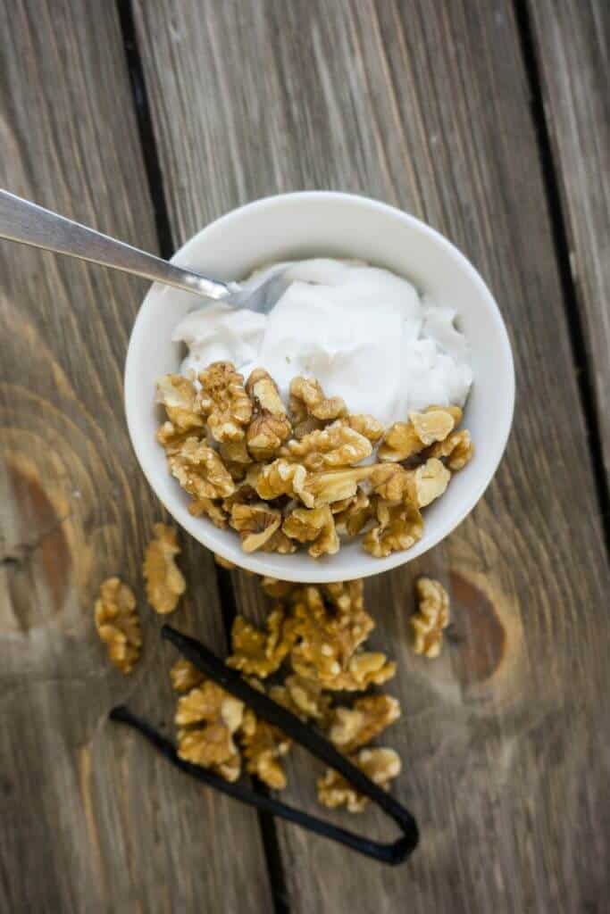 A bowl of vanilla yogurt with walnuts on top. 