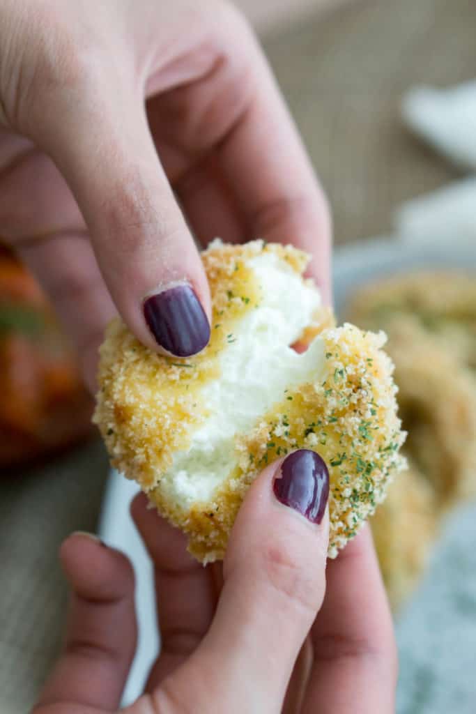 a piece of fried goat cheese being pulled apart to reveal the melted center