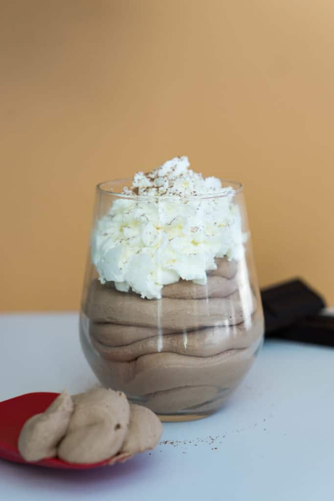 A glass filled with chocolate mousse and topped with whipped cream. 