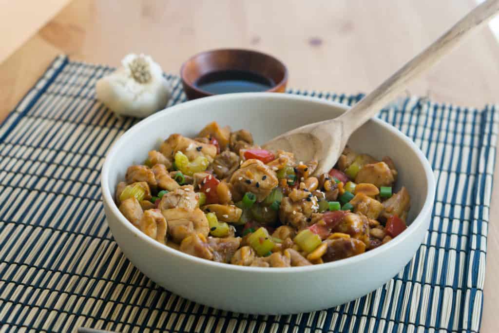 full bowl of kung pao chicken with a wooden spoon