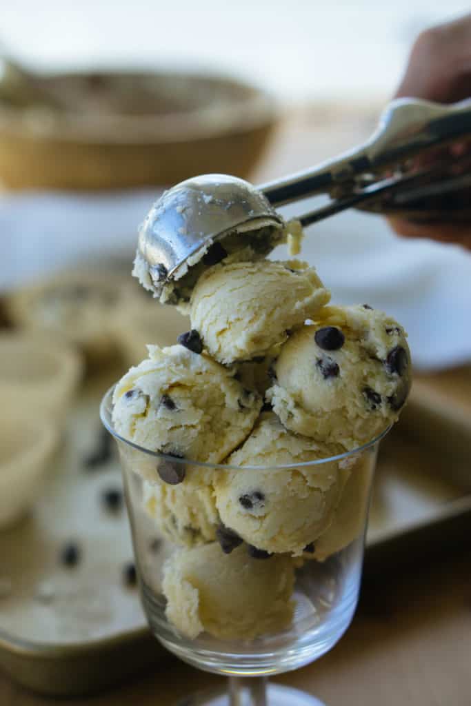 A cookie scooper forming little balls of chocolate chip cookie dough