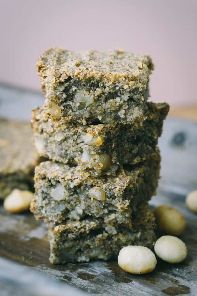 stack of 4 protein bars with chunks of macadamia nuts on a wood tray