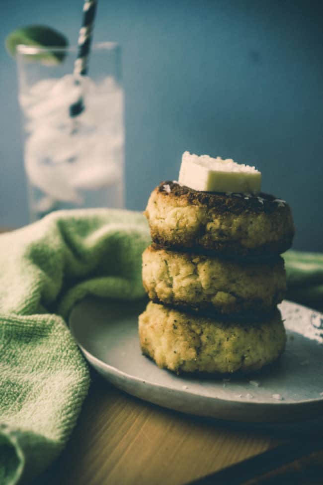 crab cakes stacked on a plate with butter on top of them