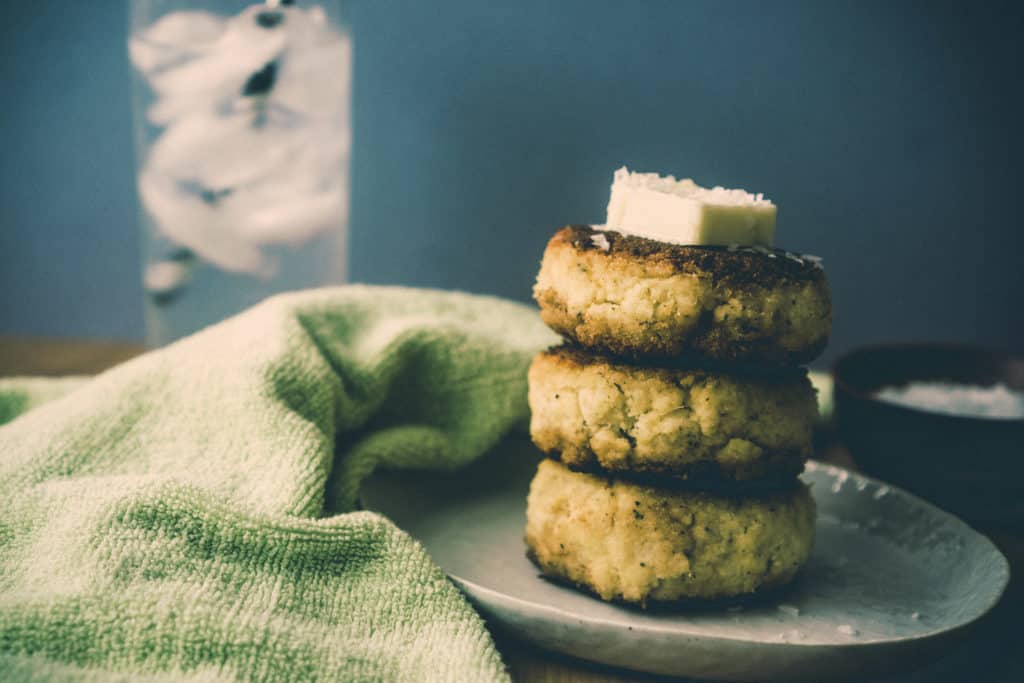 crab cakes on a plate with a slice of butter on top of them