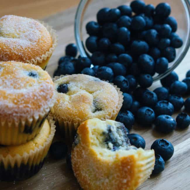 muffins in front of a spilling bowl of blueberries