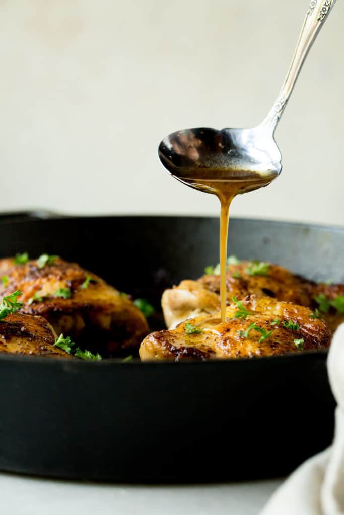 A deep cast iron with crispy chicken thighs and a linen towel