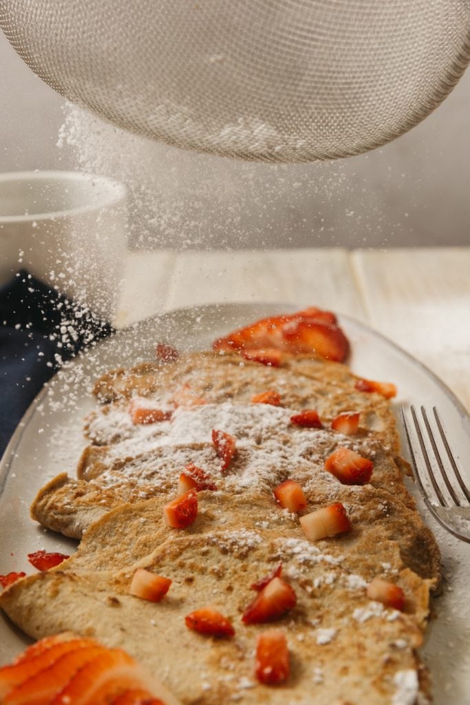 Keto Crepes adding powdered sugar to keto crepes
