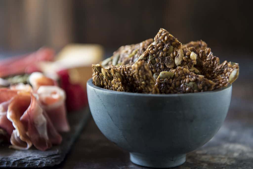 rustic bowl overflowing with keto crackers and a charcuterie board in the background