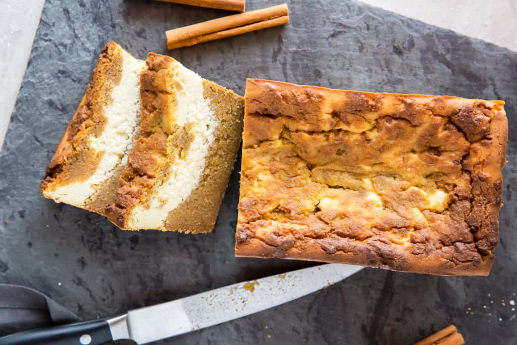Pan de calabaza bajo en carbohidratos pan relleno de crema de queso siendo cortado en una tabla de cortar