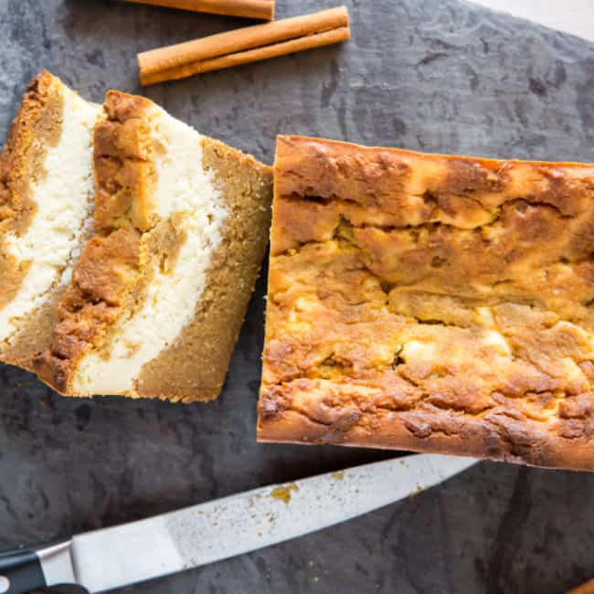 low carb pumpkin bread filled with cream cheese being sliced on a cutting board