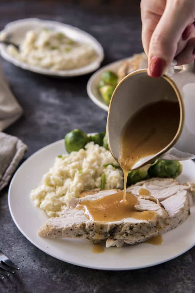 hand pouring gravy over turkey and mashed cauliflower keto side dishes