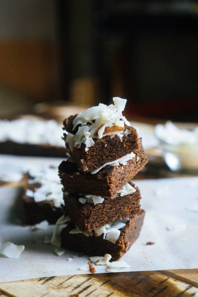 A stack of chocolate brownies topped with coconut flakes. 