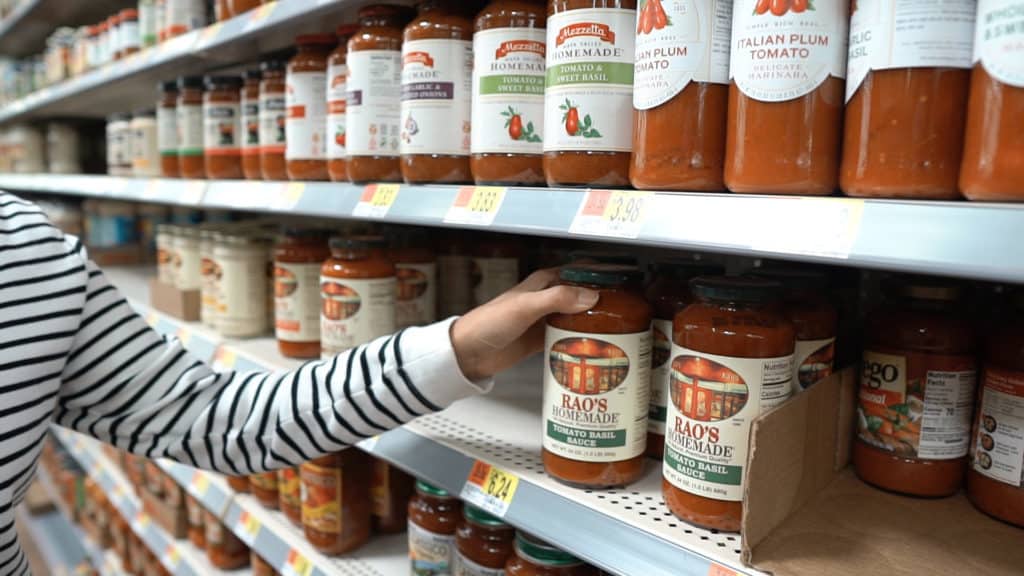 hand reaching for marinara on a shelf next to other sauces