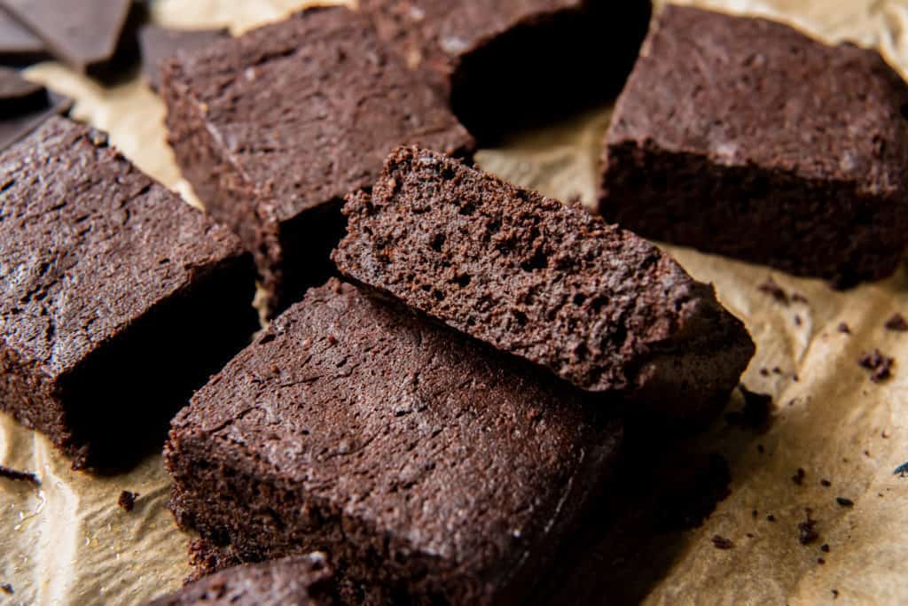 keto chocolate A fudgy keto brownie laying beside others on a piece of parchment paper
