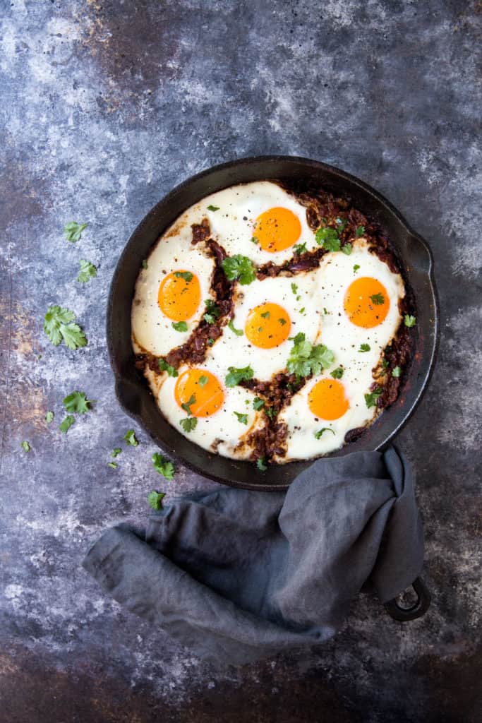 indian-eggs-far The masala baked Indian eggs cooked in a cast iron skillet with a hand towel covering the handle