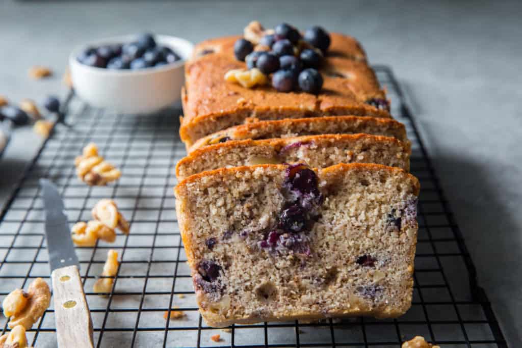 A sliced loaf of pound cake topped with blueberries