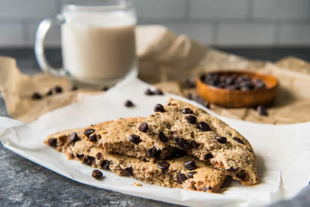 an easy air fryer cookie broken up on parchment paper with chocolate chips and a coffee in the background