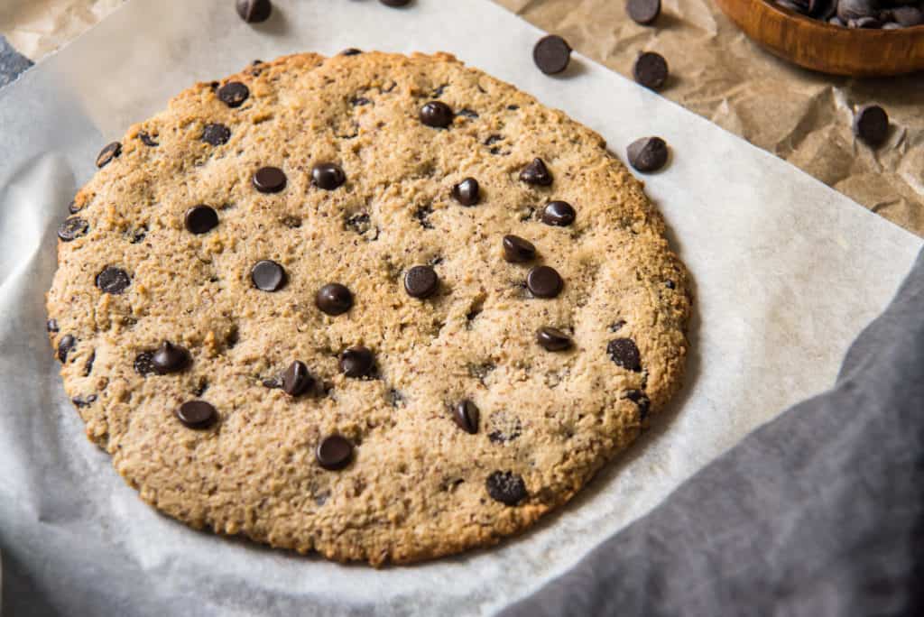 air fryer cookie an easy air fryer cookie on white parchment paper surrounded by chocolate chipe