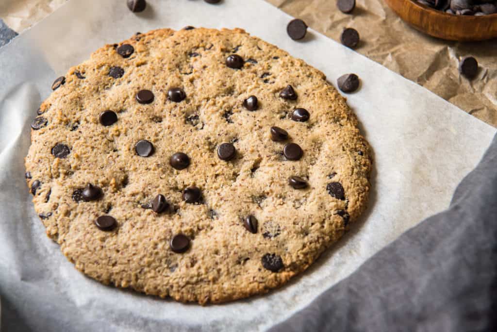 an easy air fryer cookie on white parchment paper surrounded by chocolate chipe