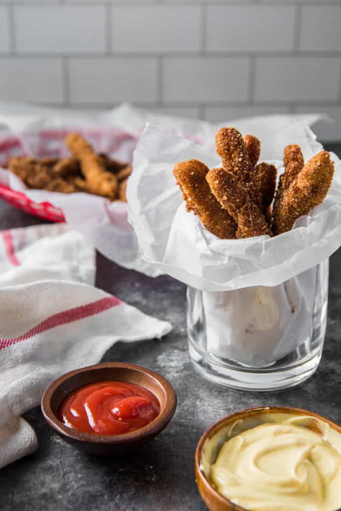 Crispy chicken fries with ketchup near a soft white and red cloth