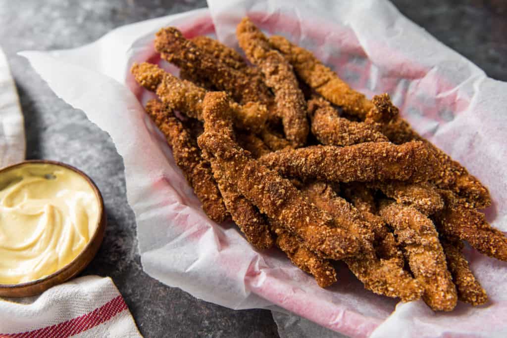 A basket of keto chicken fries next to dipping sauces