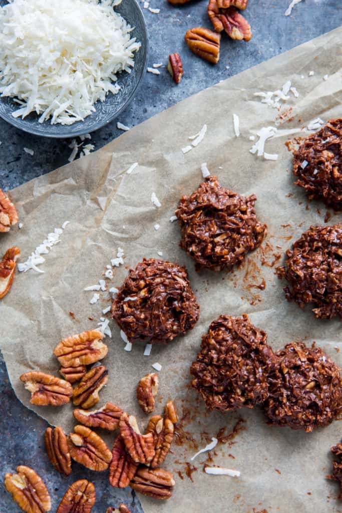 No bake cookies lined up on parchment paper next to pecan mix-ins