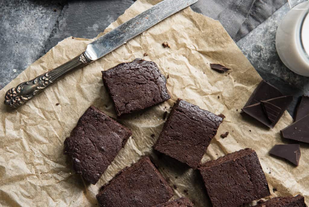 keto brownies cut and placed on parchment paper with a butter knife.