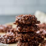 chocolate keto no bake cookies stacked on top of each other with pecans in the background