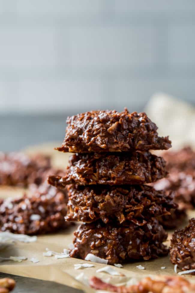 chocolate keto no bake cookies stacked on top of each other with pecans in the background