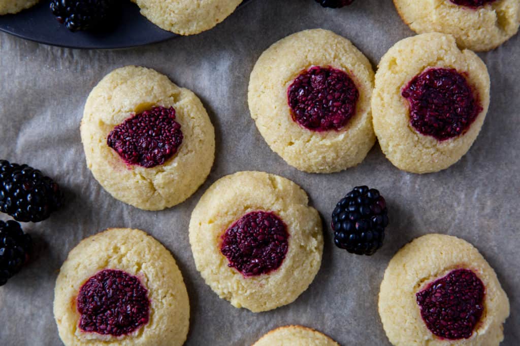easy thumbprint cookies on parchment paper surrounded by fresh blackberries