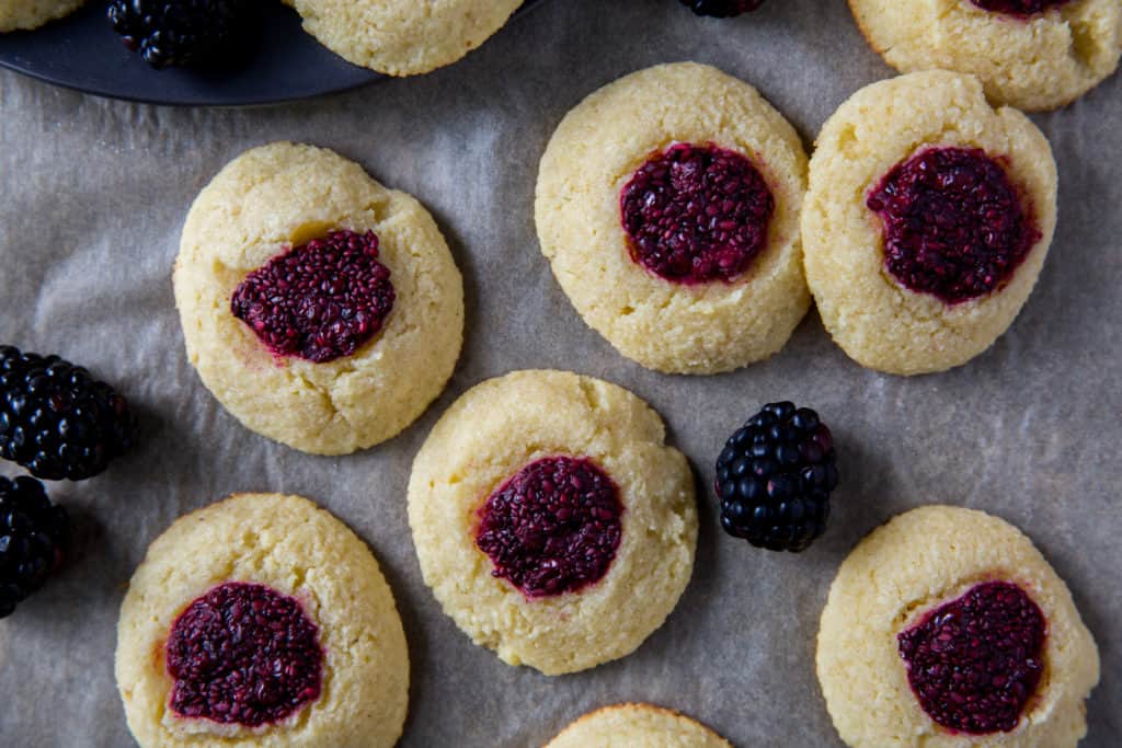 Easy Thumbprint Cookies easy thumbprint cookies on parchment paper surrounded by fresh blackberries