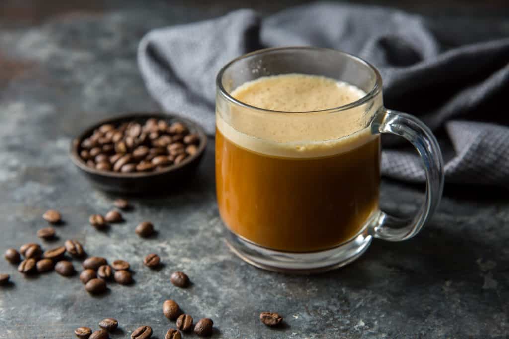 Bulletproof Coffee keto coffee on a table with a bowl of coffee beans in the background
