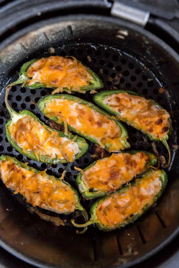 seven cooked air fryer jalapeno poppers in the air fryer basket 