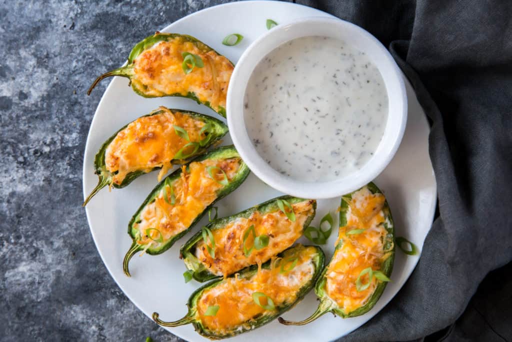 jalapeno poppers on a plate with a side of dipping sauce