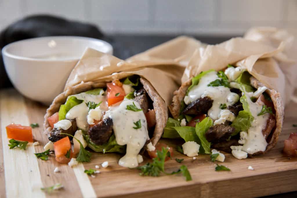 two gyros with yogurt sauce for dipping. 