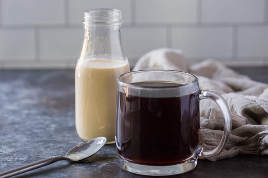 keto creamer behind a cup of black coffee