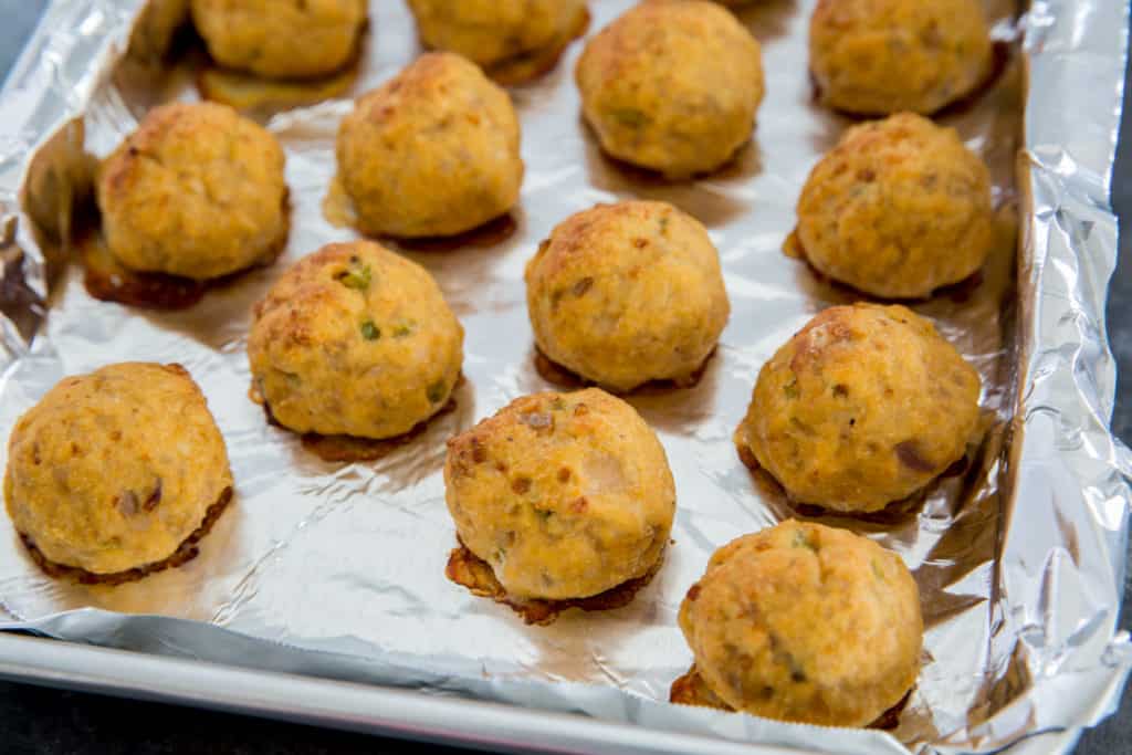 cooked buffalo chicken meatballs on a foil lined baking sheet