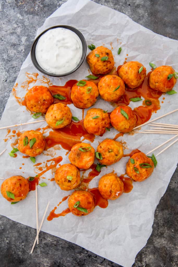 buffalo chicken meatballs with toothpicks by a dish of ranch
