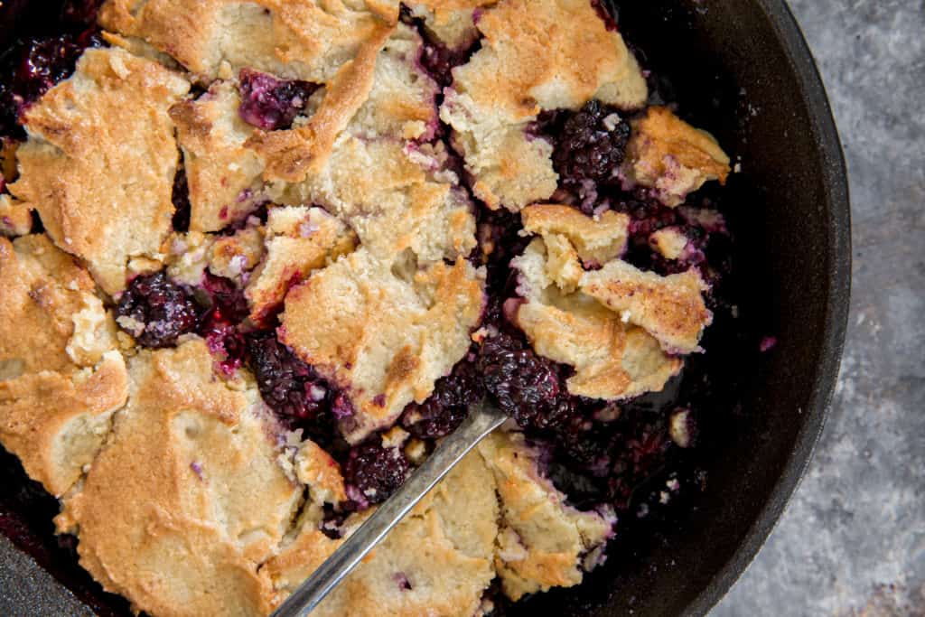 keto blackberry cobbler baked in a cast iron skillet with a spoon