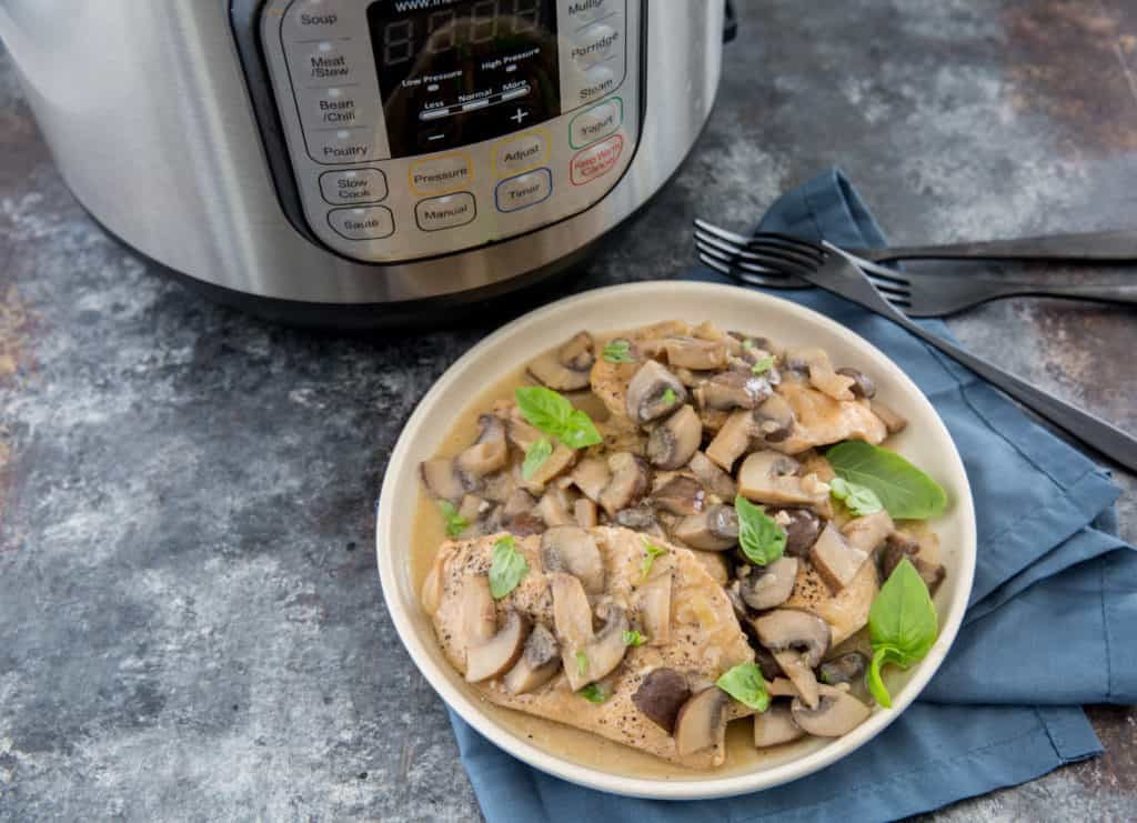 Instant pot chicken marsala served on a white plate with an instant pot in the background