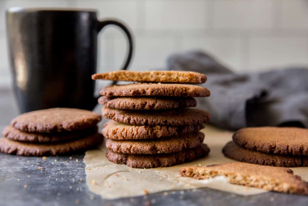 three stacks of keto ginger cookies with a coffee mug in the background